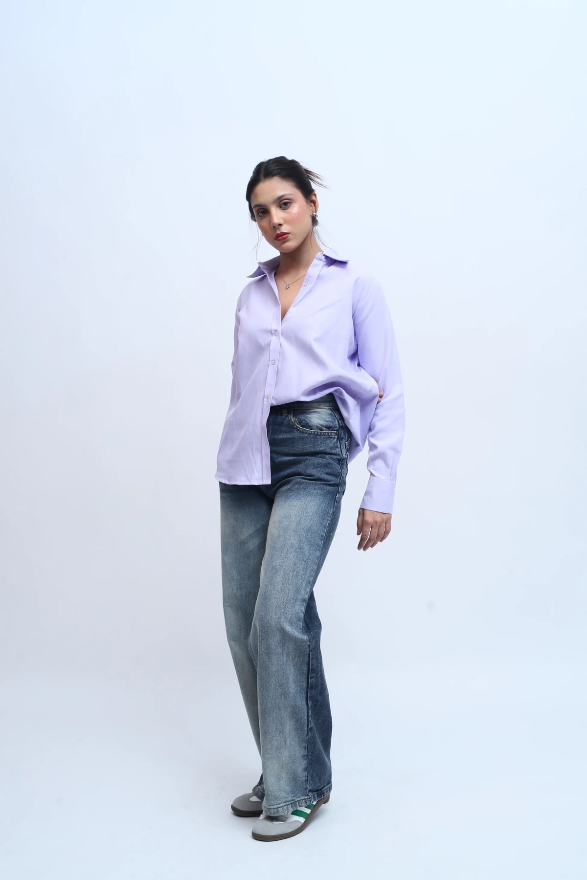 Woman wearing a lavender button-down shirt and baggy blue denim jeans.