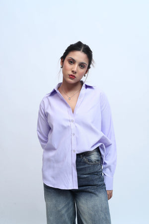 Woman wearing a lilac button-down shirt and blue denim jeans against a white background.