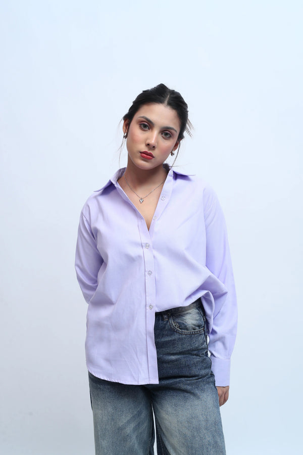 Woman wearing a lilac button-down shirt and blue denim jeans against a white background.