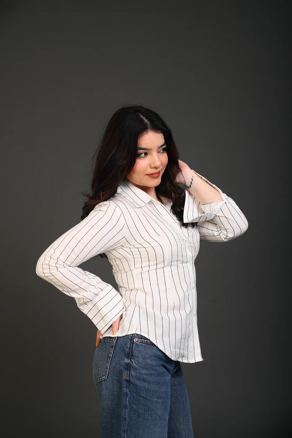 Woman wearing a white striped button-down shirt and blue denim jeans.