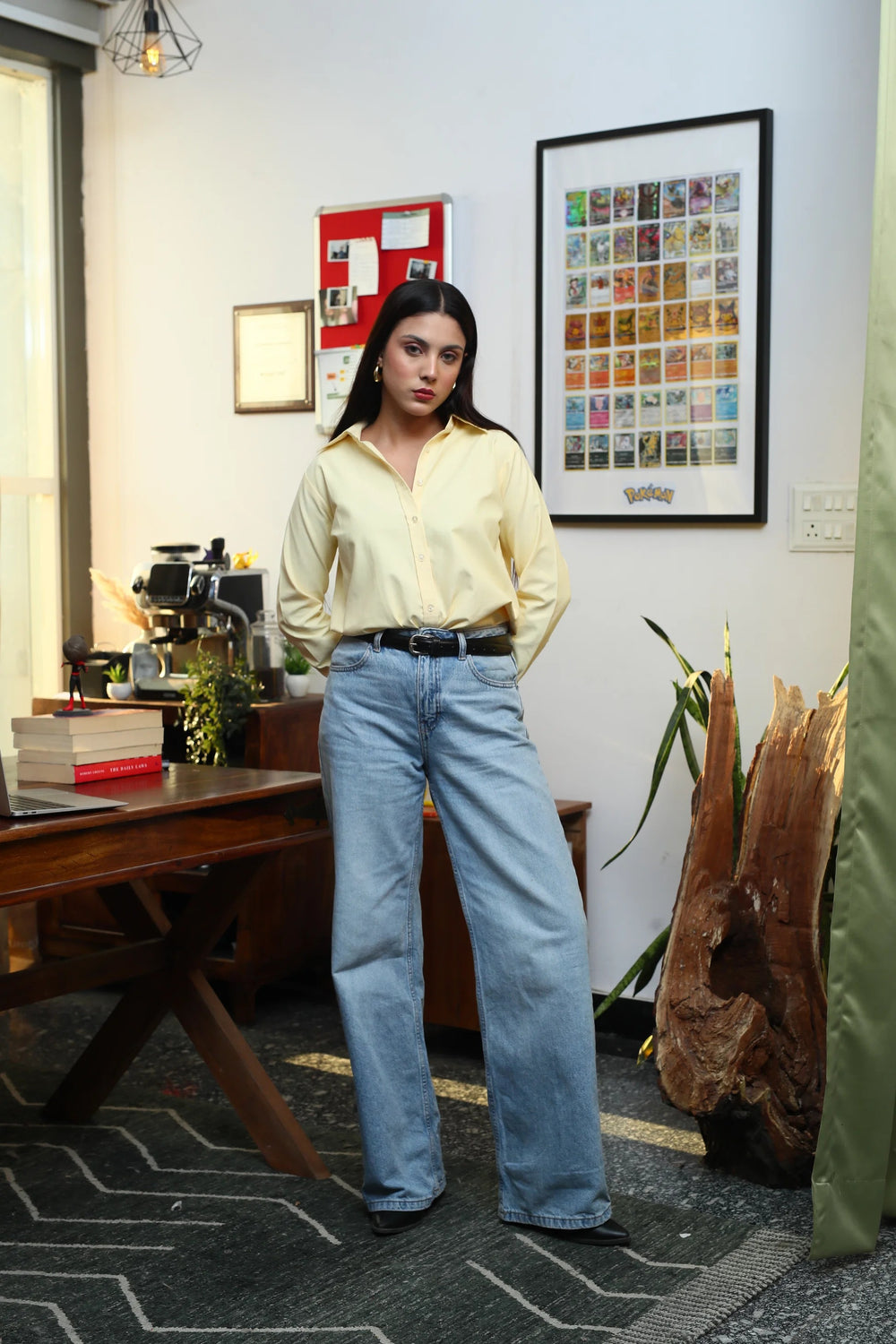 Woman wearing a pale yellow button-down shirt and light blue wide-leg denim jeans.
