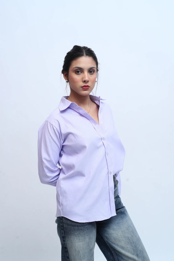 Woman wearing a light purple button-down shirt and blue denim jeans.