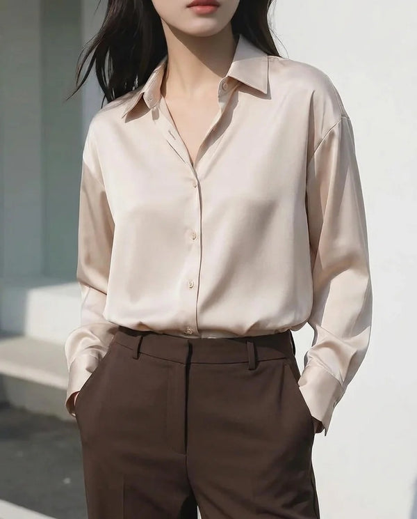 Woman wearing a beige satin button-down shirt and brown high-waisted trousers.