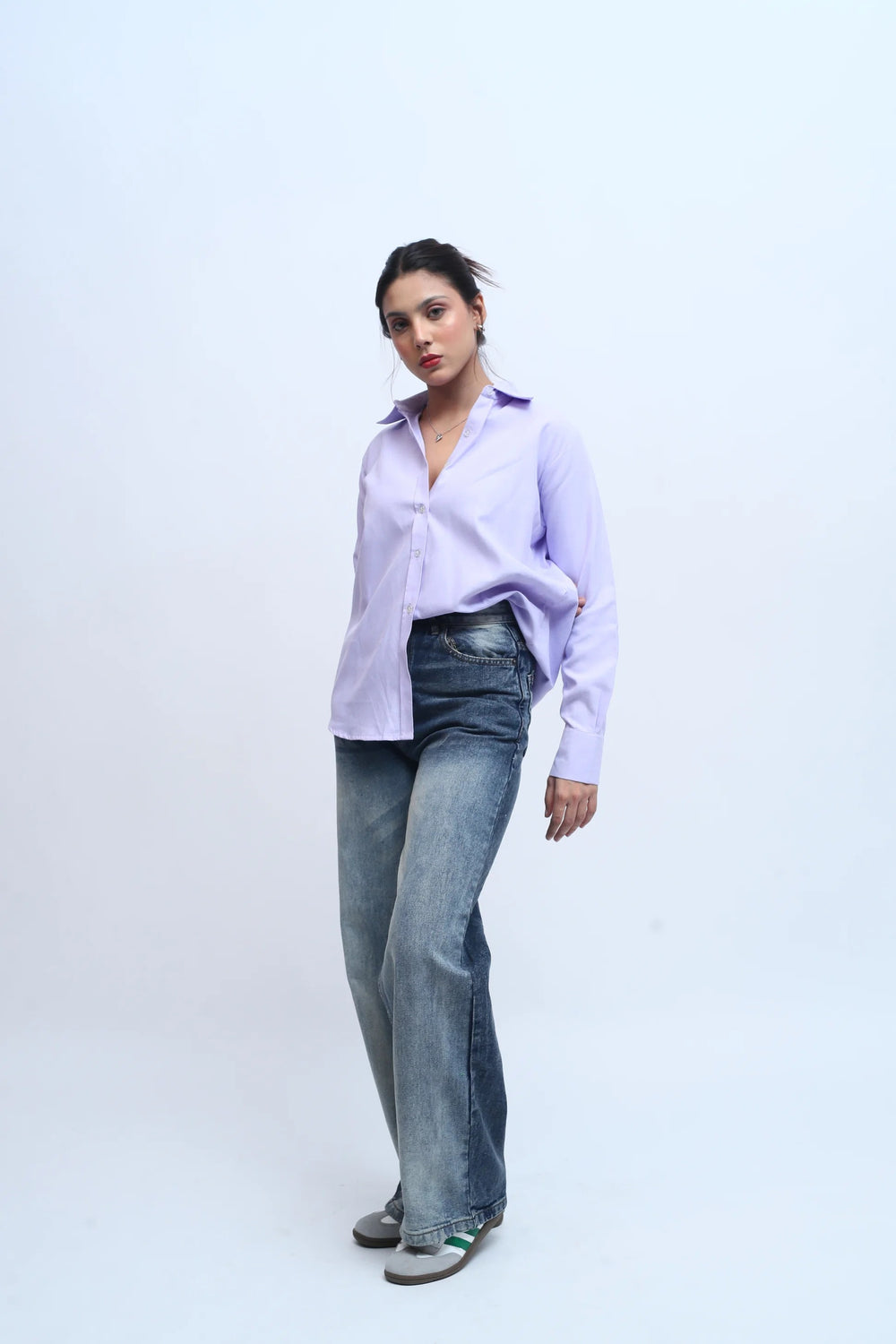Woman wearing a light purple button-down shirt and blue denim jeans.