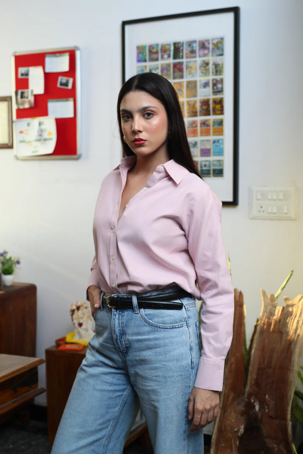 Woman wearing a light pink button-down shirt and light wash denim jeans.